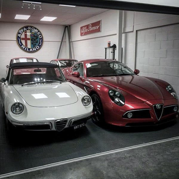 A compact garage showcasing classic and modern Alfa Romeo cars, with a clean ceiling and branded decor.