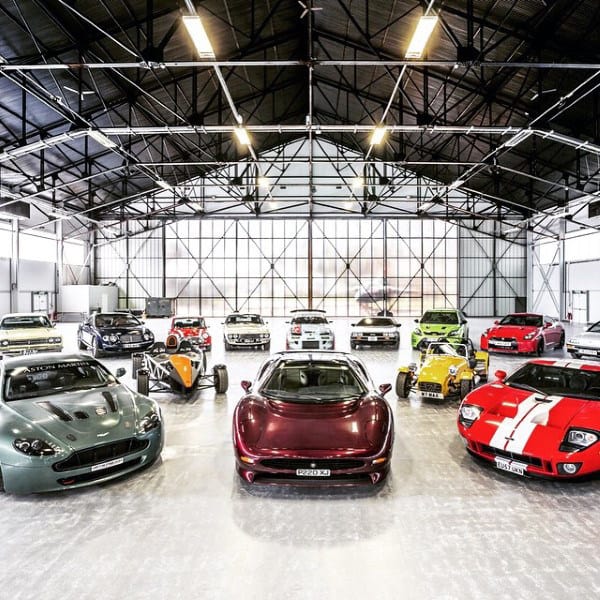 An impressive dream garage featuring a diverse collection of exotic cars under a vast, industrial-style roof.
