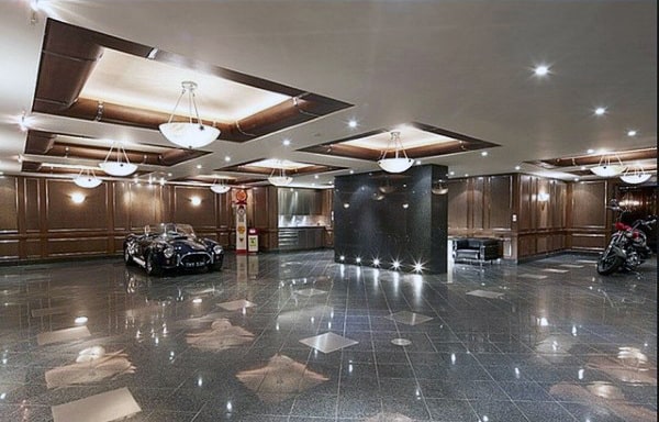 A luxurious garage featuring polished floors, elegant wood-paneled walls, recessed lighting, and sophisticated ceiling designs with chandeliers.