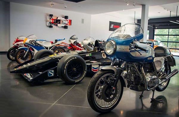 A sleek garage showcasing motorcycles and a Formula 1 car with a polished floor and modern decor.