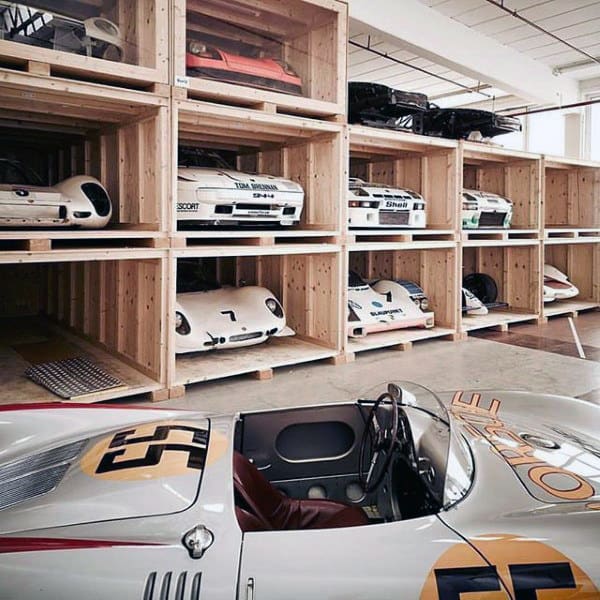 A dream garage featuring a well-organized display of classic race cars stored in custom wooden crates, ideal for preservation and style.