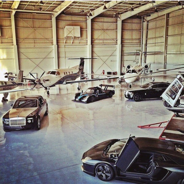 A spacious hangar-style garage showcasing private jets and luxury cars in a sleek, open layout.