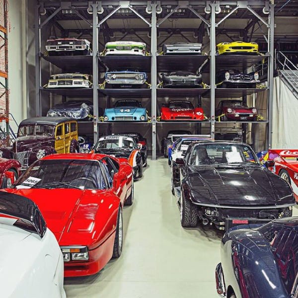 A dream garage showcasing classic and tuned cars with efficient multi-tiered storage racks.
