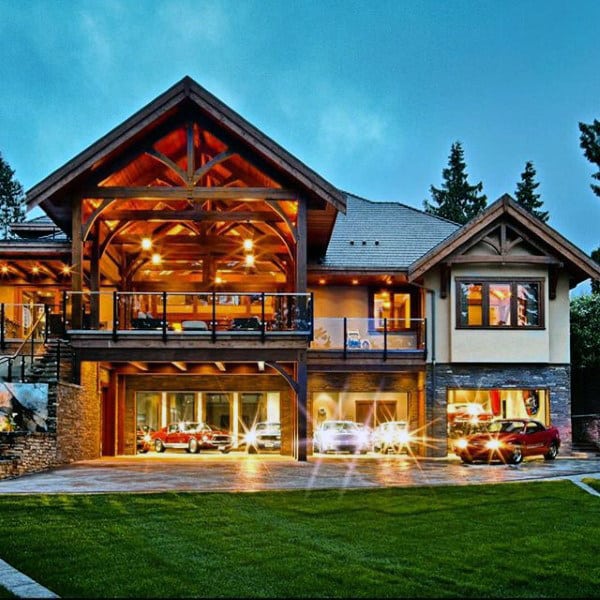 A stunning luxury home with an attached garage featuring floor-to-ceiling glass doors showcasing high-end cars, blending modern architecture with rustic timber elements.