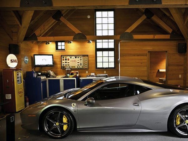 A sleek gray sports car parked in a rustic wooden garage adorned with vintage decor and memorabilia