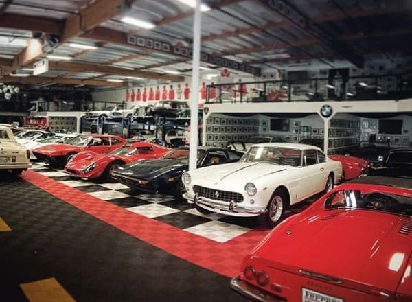 Classic garage featuring a checkered floor, vintage Ferraris, and a well-organized luxury car collection.