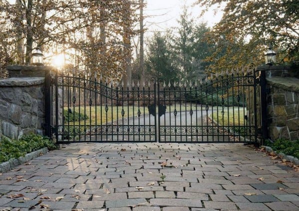 Ornate iron driveway gate with pointed finials and decorative scrollwork.