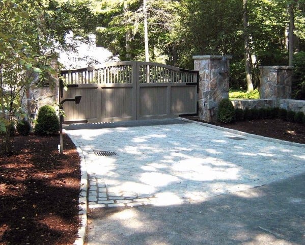 Gray wooden driveway gate with arched top and solid panel design.