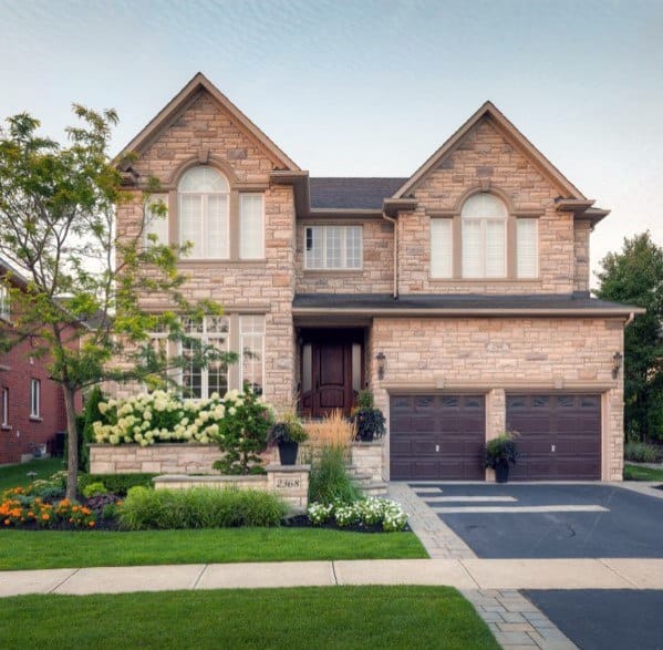 Asphalt driveway with a smooth finish and light stone paver borders leading to a traditional-style home.