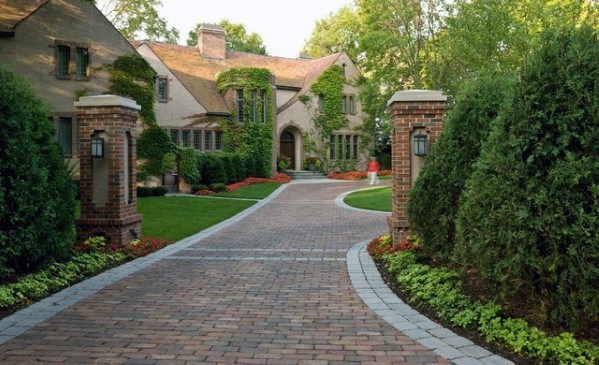Brick-paved driveway with a subtle curve and light gray stone edging.