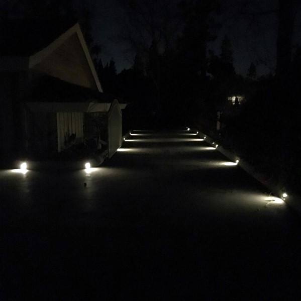 Driveway illuminated by subtle ground lighting, casting a soft glow along the path at night