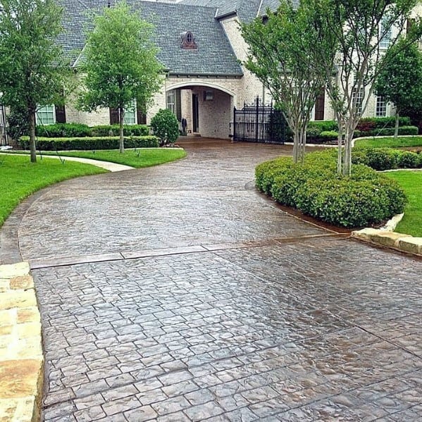 Stamped concrete driveway with a curved layout and a textured brick-like surface pattern.