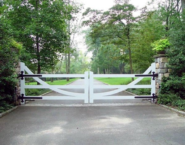 White wooden driveway gate with a traditional cross-brace design and black hardware.