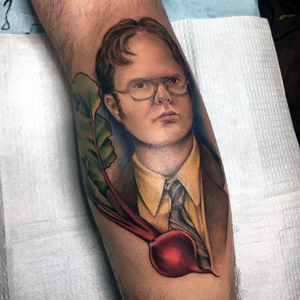 Realistic tattoo of Dwight Schrute wearing glasses and a suit, seamlessly blending into a beet with detailed shading and vibrant colors on a leg.