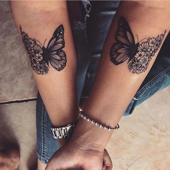 Matching forearm tattoos featuring a butterfly with wings blending into sunflower designs, combining nature and symmetry in black ink.
