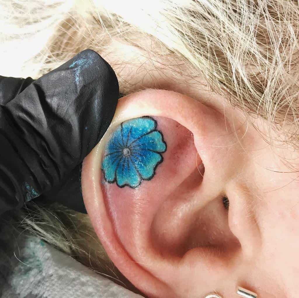 Blue flower tattoo inside an ear