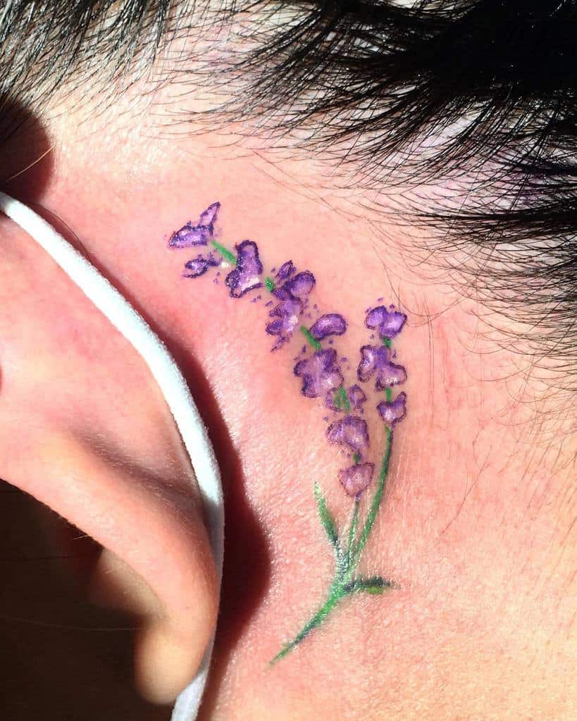 A delicate lavender tattoo behind an ear