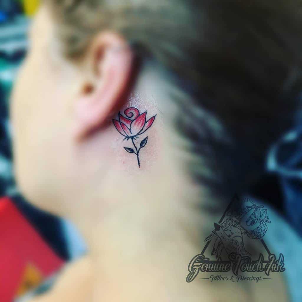 A small rose tattoo on the side of a person's neck
