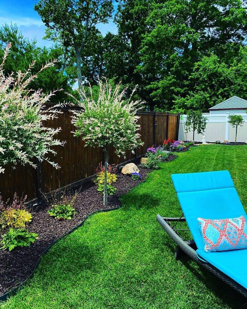 green grass garden with mulch and small plants blue sun lounger 