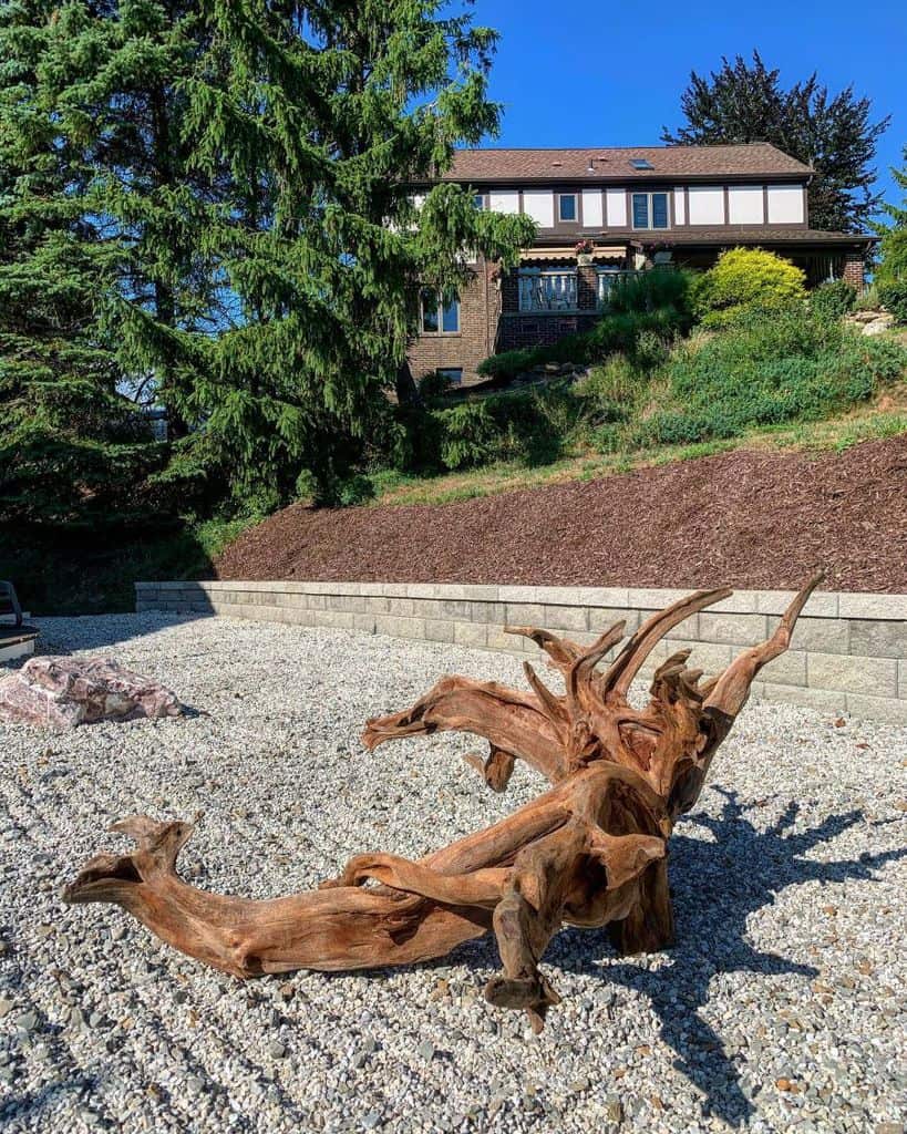 strange wood sculpture gravel garden front yard 