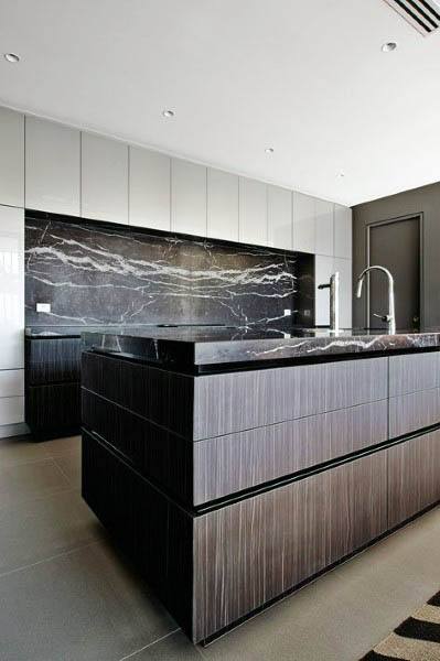 Modern kitchen with dark wood cabinets, black marble backsplash, and minimalist design.