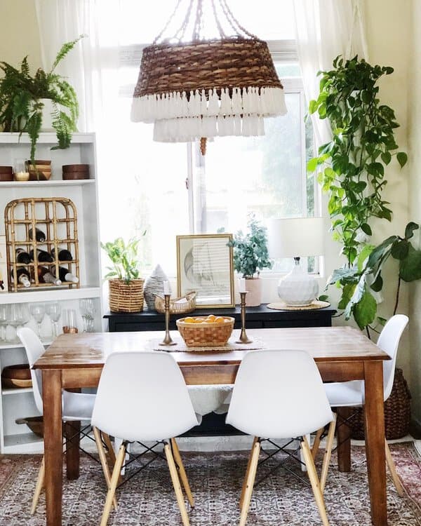 Eclectic boho dining room with natural lighting, woven pendant light, and plants.
