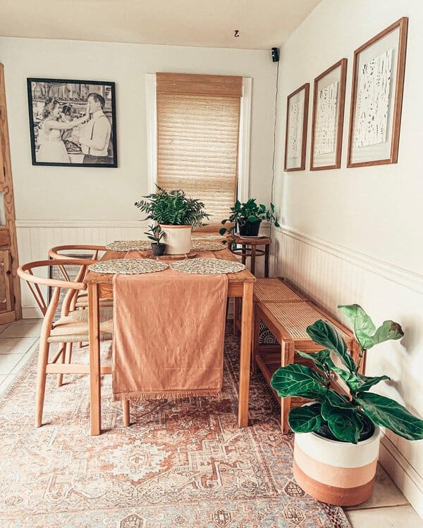 Eclectic boho dining area with wooden furniture, plants, and cozy, earthy tones.