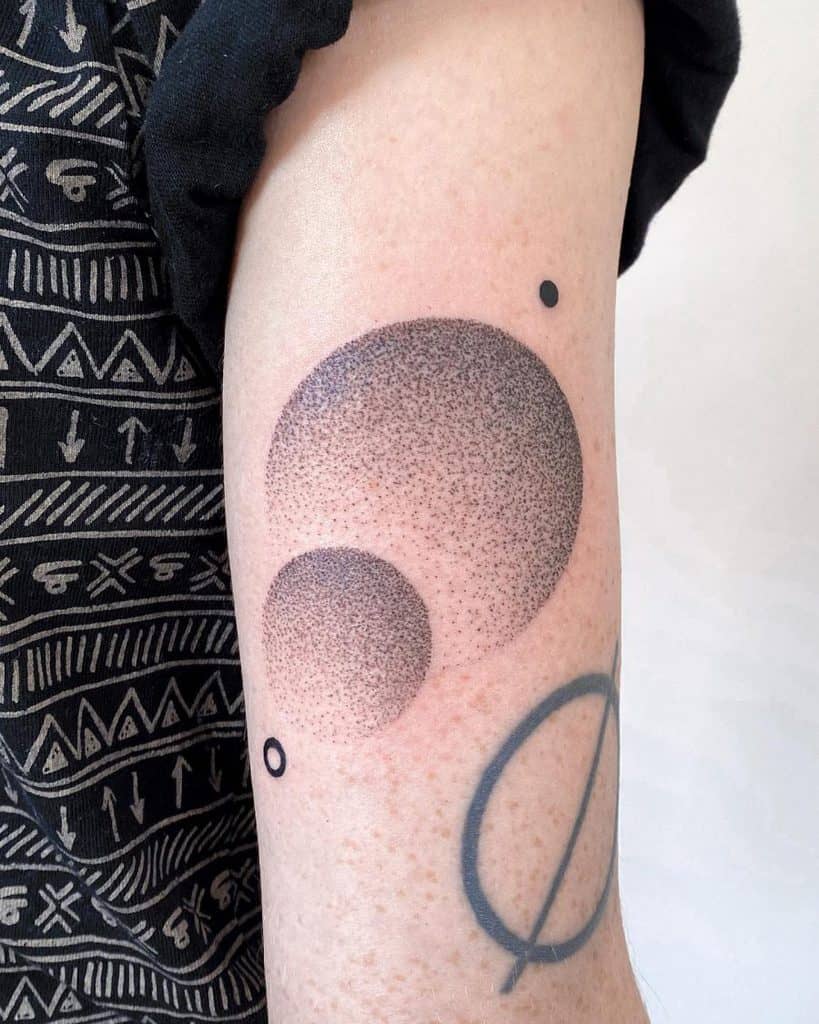 Minimalist arm tattoo featuring two overlapping celestial bodies created with fine dot work, blending geometric and cosmic aesthetics.
