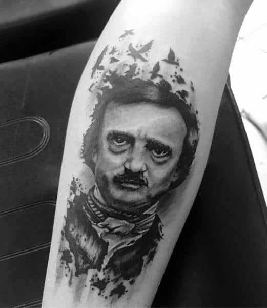 Black and grey tattoo of Edgar Allan Poe with a realistic face, surrounded by flying birds and ink-like splatter effects.
