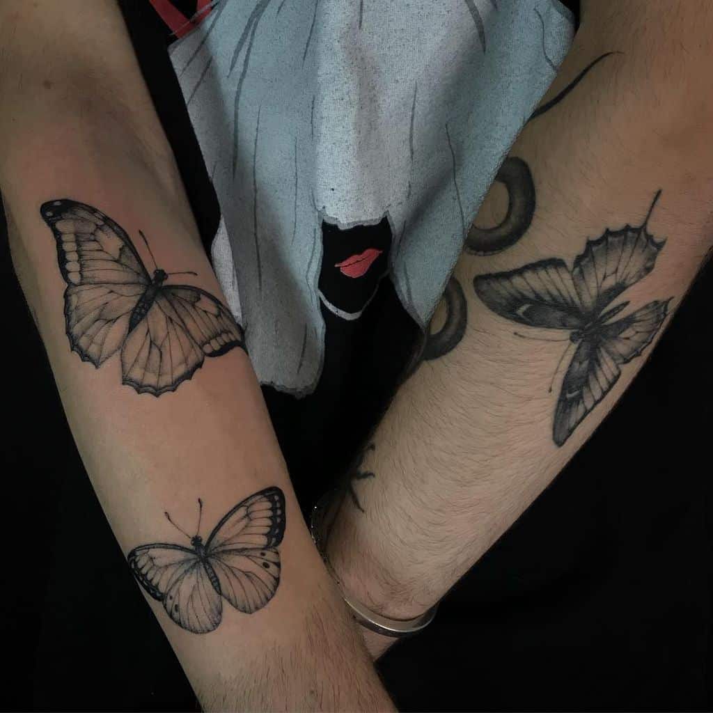 Black and gray butterfly tattoos on both forearms, featuring fine shading and intricate wing details for a realistic and artistic design.