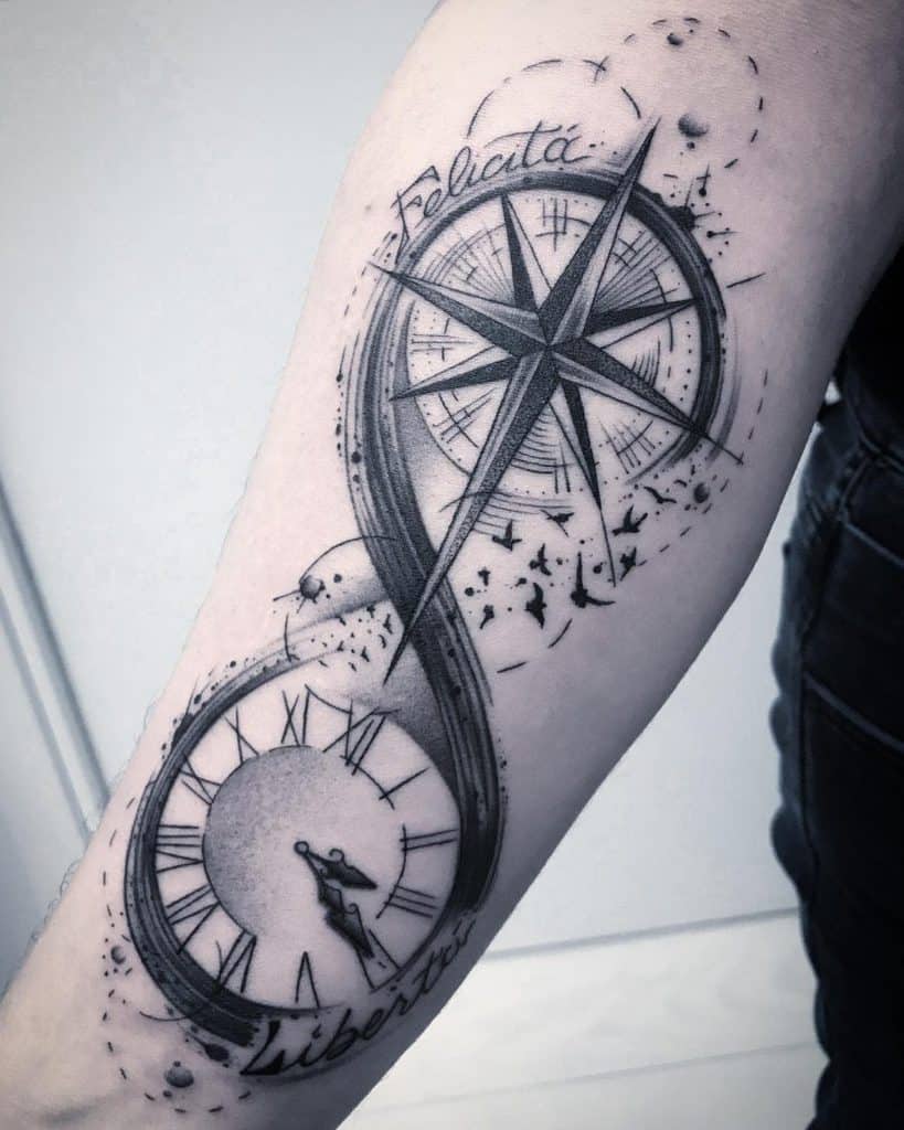 This tattoo features the infinity symbol intertwined with various elements, such as a compass and clock, incorporating the words "Felicità" (happiness) and "Libertà" (freedom). The compass represents guidance and direction, while the clock could symbolize the passage of time, adding a philosophical or personal meaning to the tattoo. The overall design exudes a sense of continuity, freedom, and happiness.