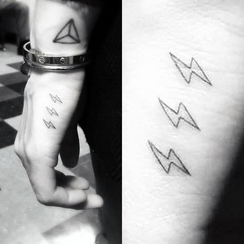 Side hand tattoo for men showing three small, minimalist lightning bolts stacked vertically on the outer edge of the hand.
