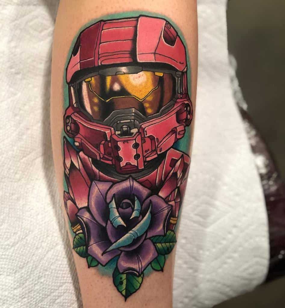 Vibrant Halo tattoo of a red Spartan helmet with a golden visor, surrounded by a detailed purple rose and energy crystals, inked on the forearm.
