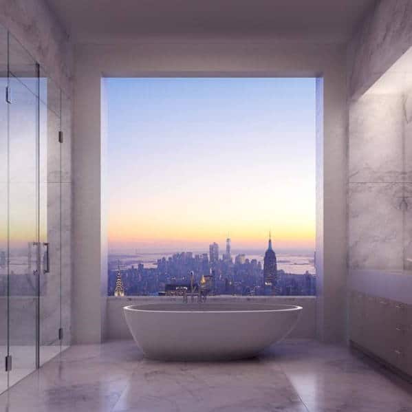 Luxurious bathroom with a bathtub and a large window showcasing a city skyline at sunset