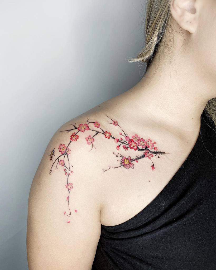 A delicate tattoo of pink cherry blossoms adorns the shoulder