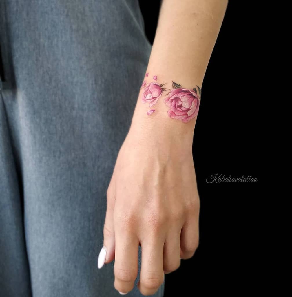 Delicate pink rose tattoo on a person's wrist