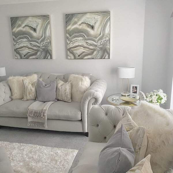 Grey and white living room with tufted sofas, plush pillows, and elegant gold accents.