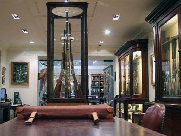 Elegant gun room showcasing rifles in glass display cases with a refined and classic design.