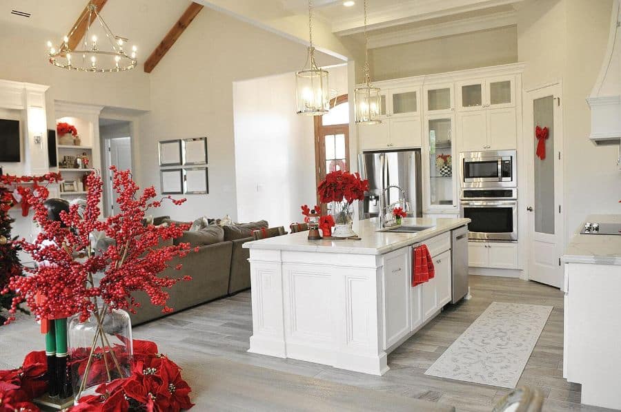 elegant white kitchen with red flowers and chandelier