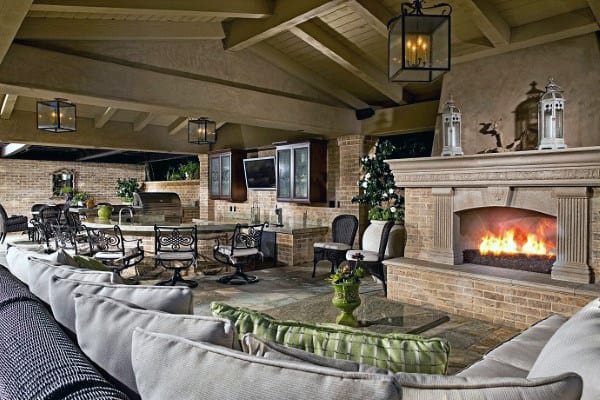 Covered patio with a fireplace, seating area, and hanging lanterns creating a cozy outdoor space