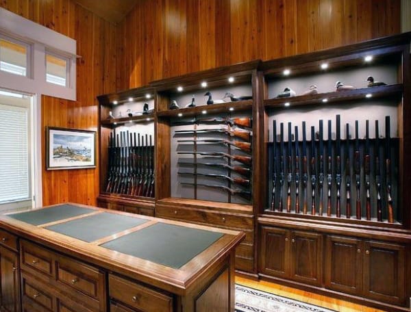 Elegant gun room with polished wooden walls, illuminated display shelves, and a functional central island.