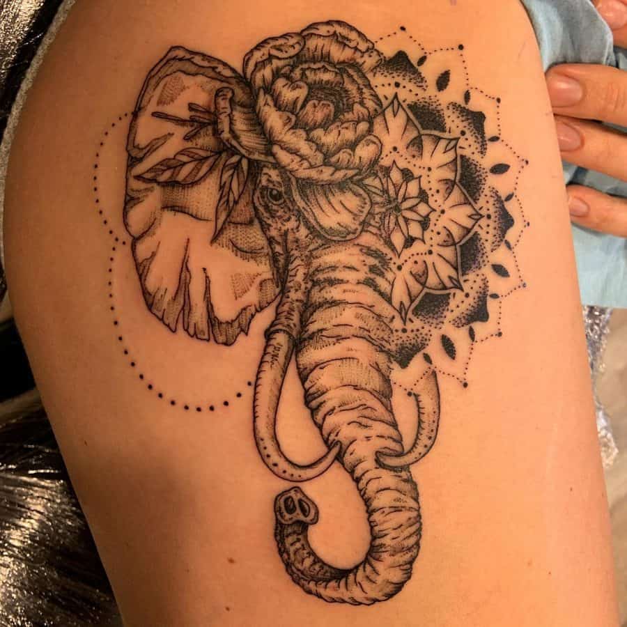 Thigh tattoo of an elephant with floral and mandala details, blending realism with intricate dot work and ornamental patterns.