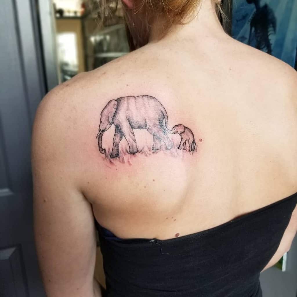 Mother-daughter tattoo of a large elephant and a small elephant on a grass