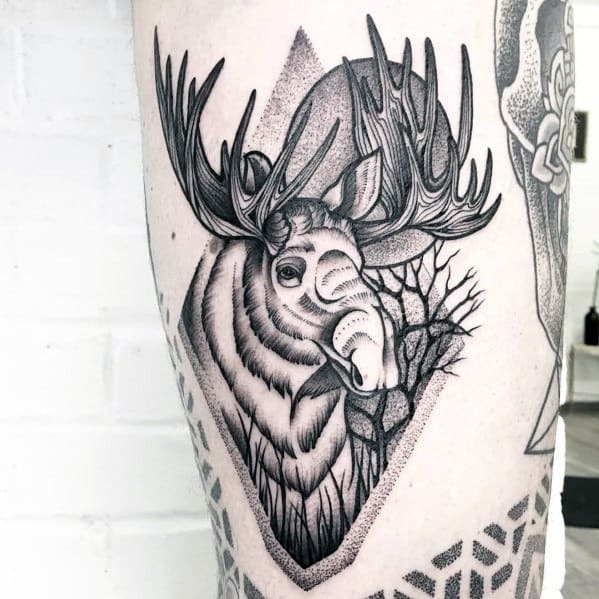 Detailed black and grey moose tattoo on the thigh, featuring bold linework, geometric elements, and a cracked tree design for a striking look.