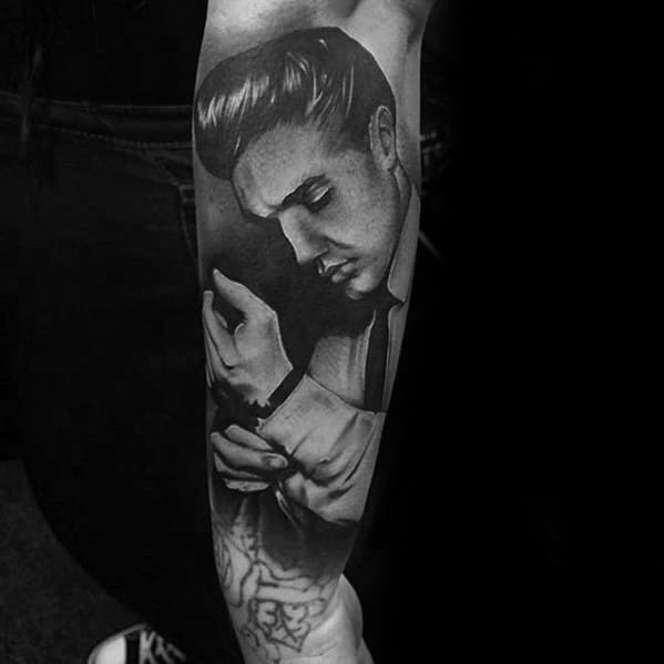 Black and grey Elvis Presley tattoo on forearm, showing him adjusting his cuff with a calm, focused expression.