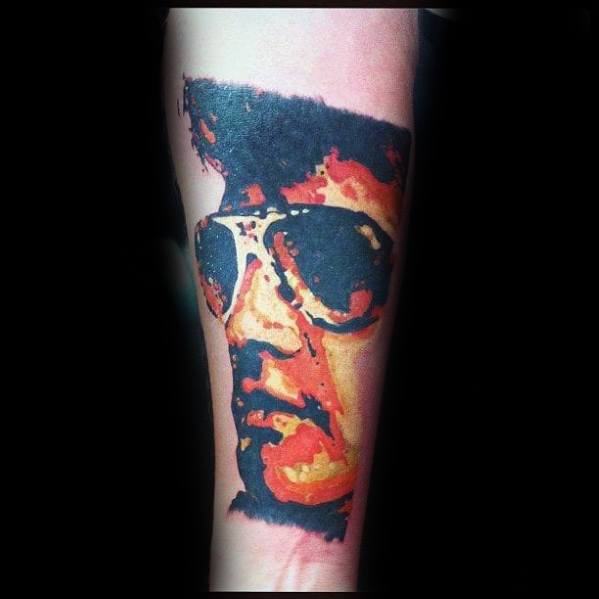 Vibrant Elvis Presley tattoo in abstract style, featuring bold orange and red tones with his signature sunglasses.