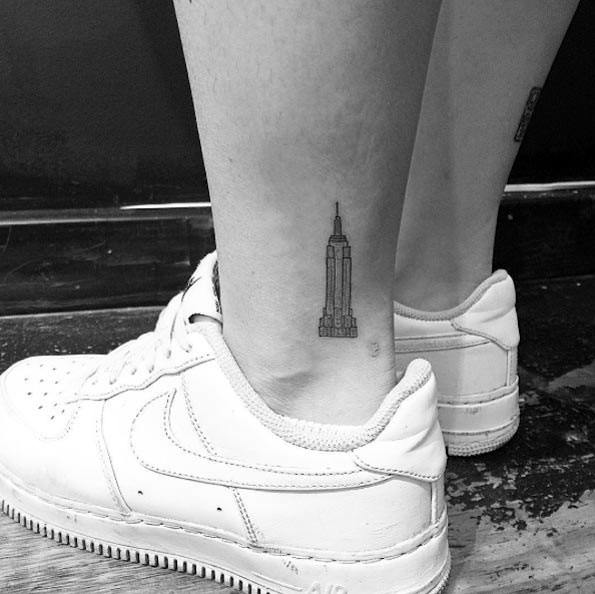 Tiny, minimalist Empire State Building tattoo delicately inked on a man's ankle.