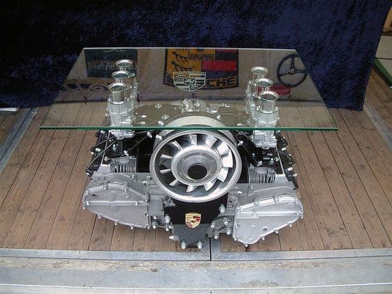 Glass table with a base made from a car engine displayed on wooden floor