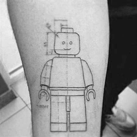 Tattoo of a LEGO figure in blueprint style with measurement lines and proportions, combining playfulness with technical design on the forearm.