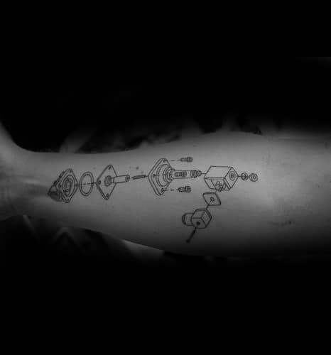 Tattoo of a detailed exploded mechanical diagram with labeled parts, resembling a technical assembly blueprint inked along the forearm.